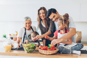Three-generation family with two small children preparing food.